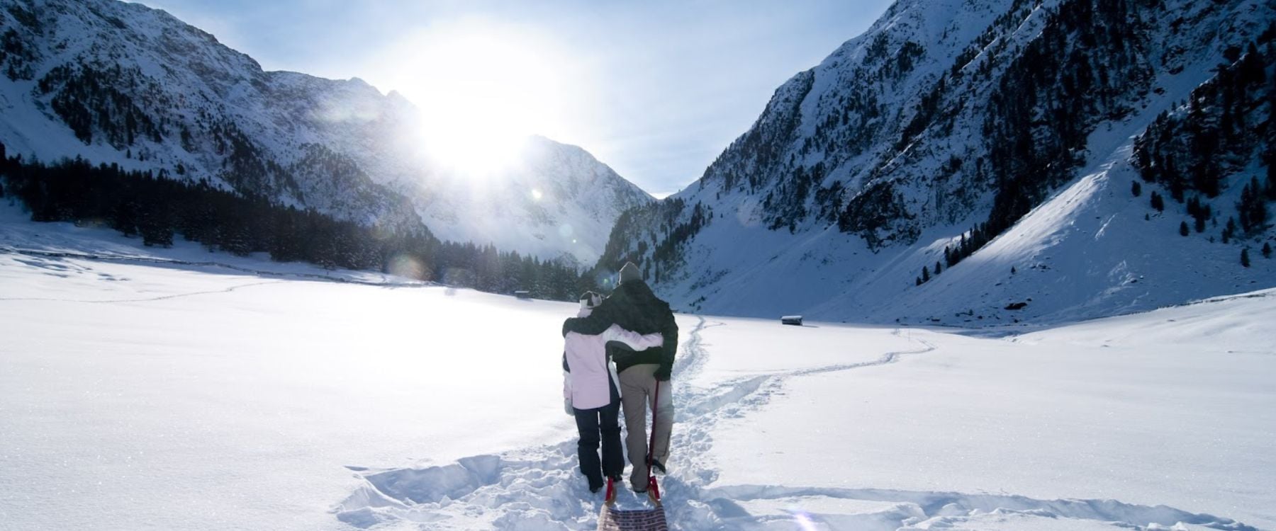 A father and daughter dragging a toboggan through the snow
