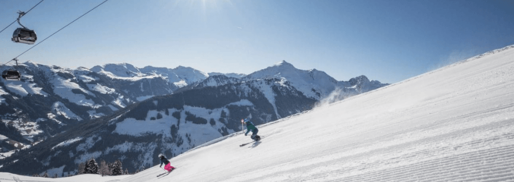 Two skiers going down a piste at a small ski resort in Austria