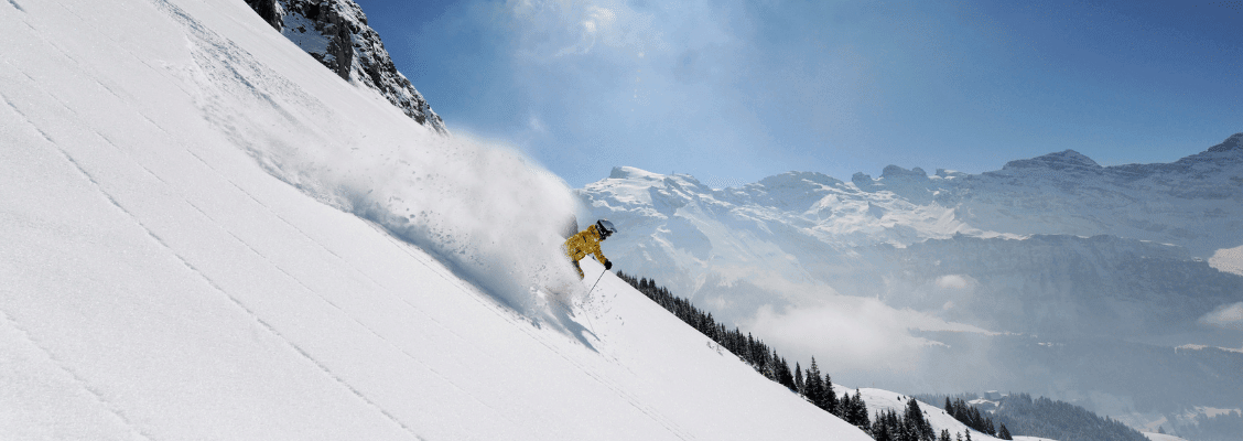 A skier skiing through powder snow on a steep mountain in Europe