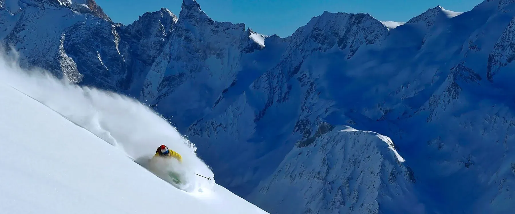 A skier in powder snow in front of a mountain range